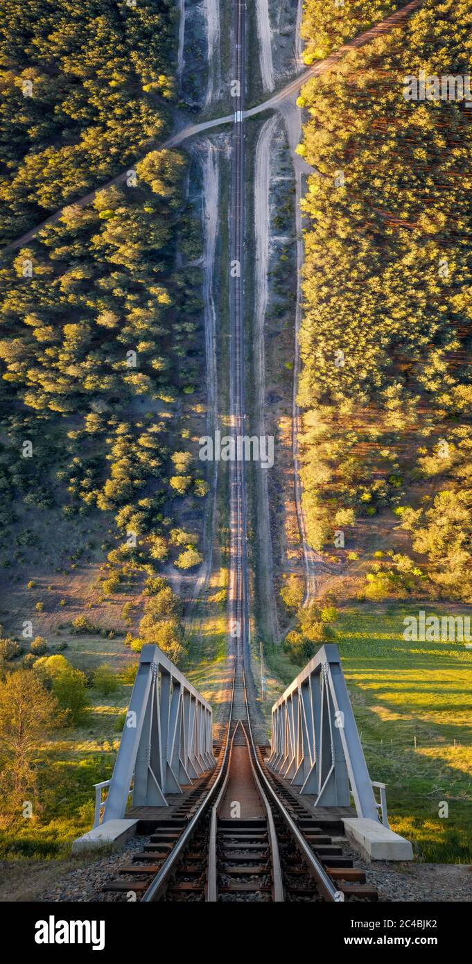 Railway with bridge among forest in warped perspective, Poland Stock Photo