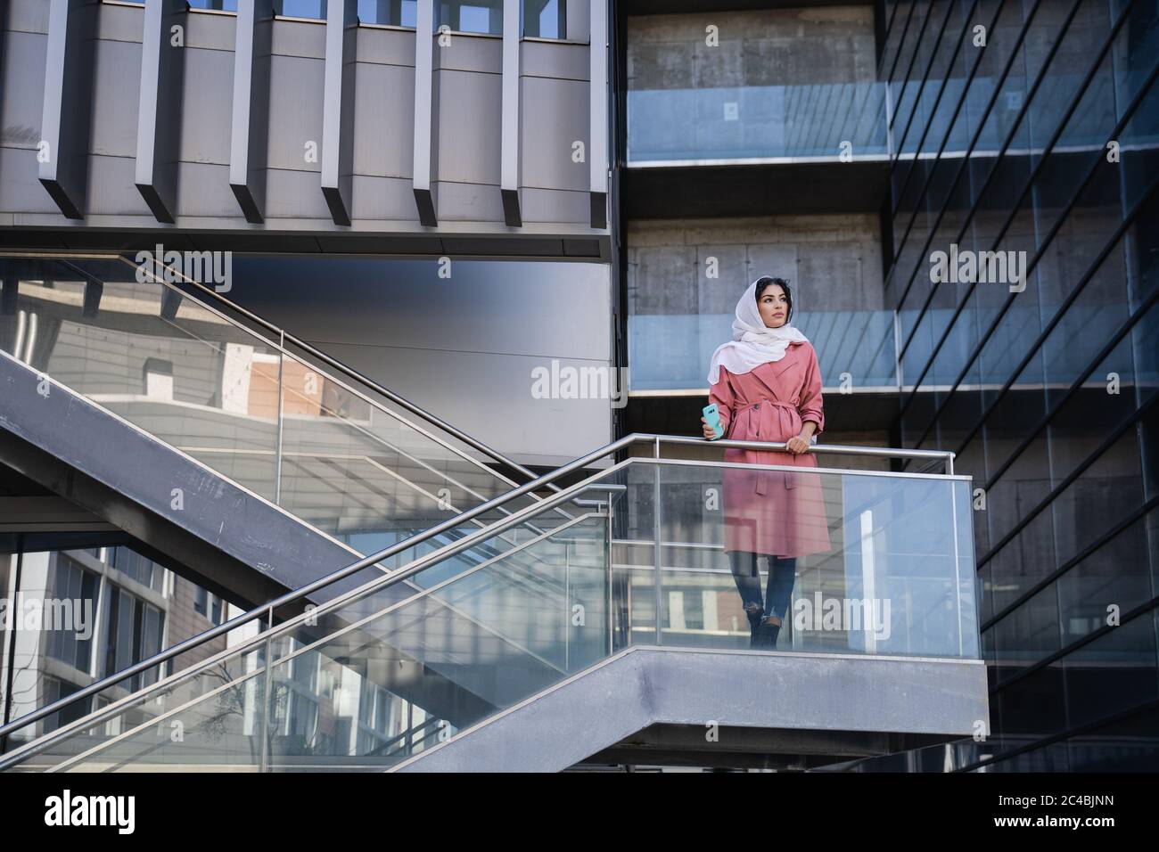 Arab young woman wearing hijab on a built structure  Stock Photo