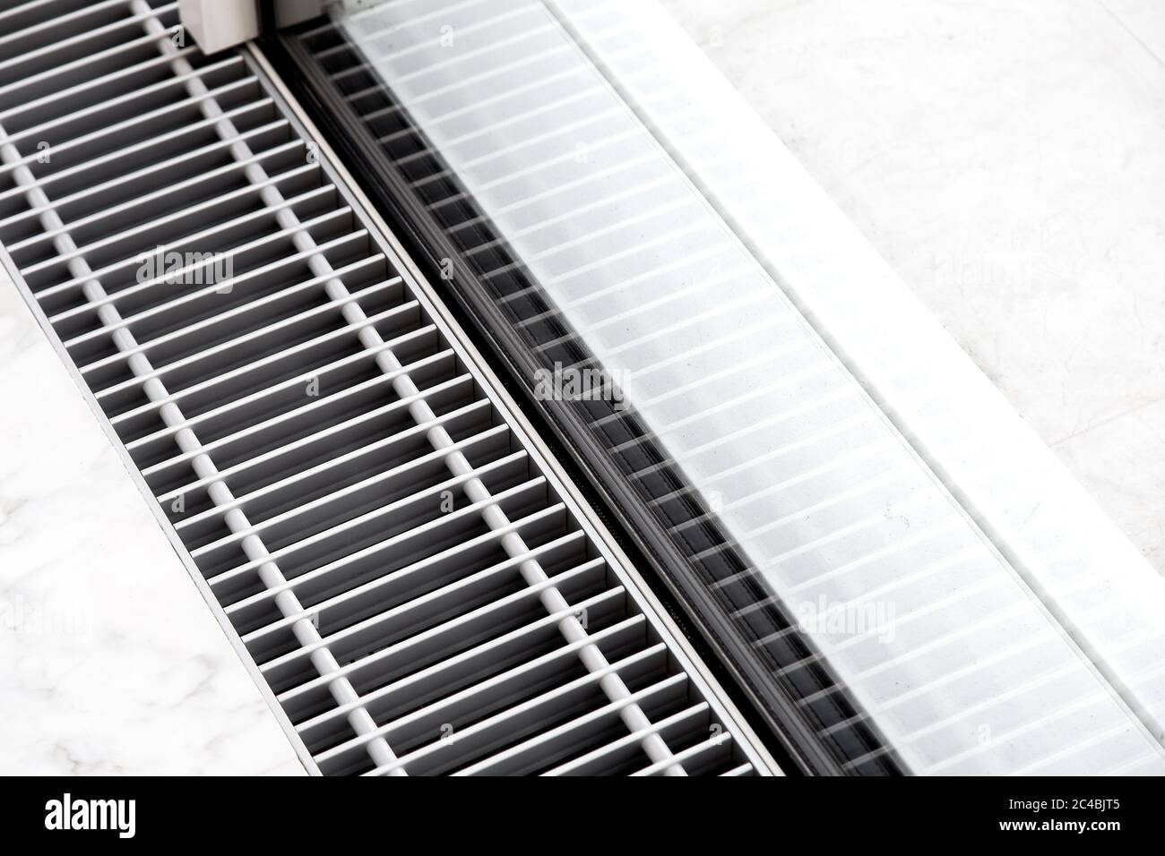Heating grille with floor ventilation in white stone flooring near the