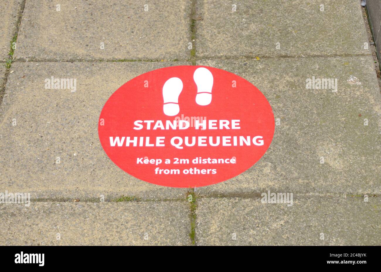 Sign on pavement outside a UK bank advising customers two keep a two metre gap while queuing during the COVID-19 coronoavirus pandemic. Stock Photo