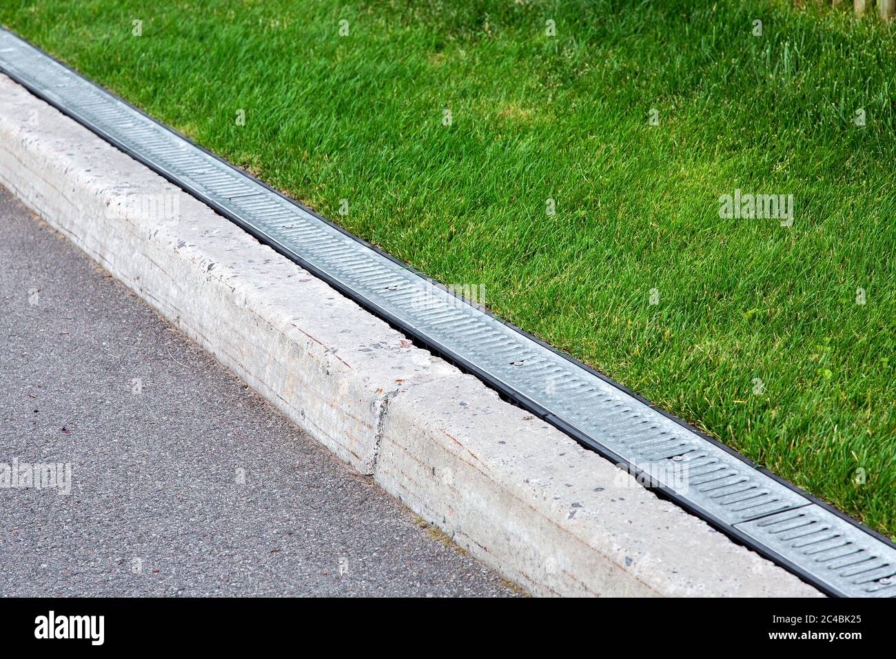 drainage system along an asphalt road with a stone curb and grill for