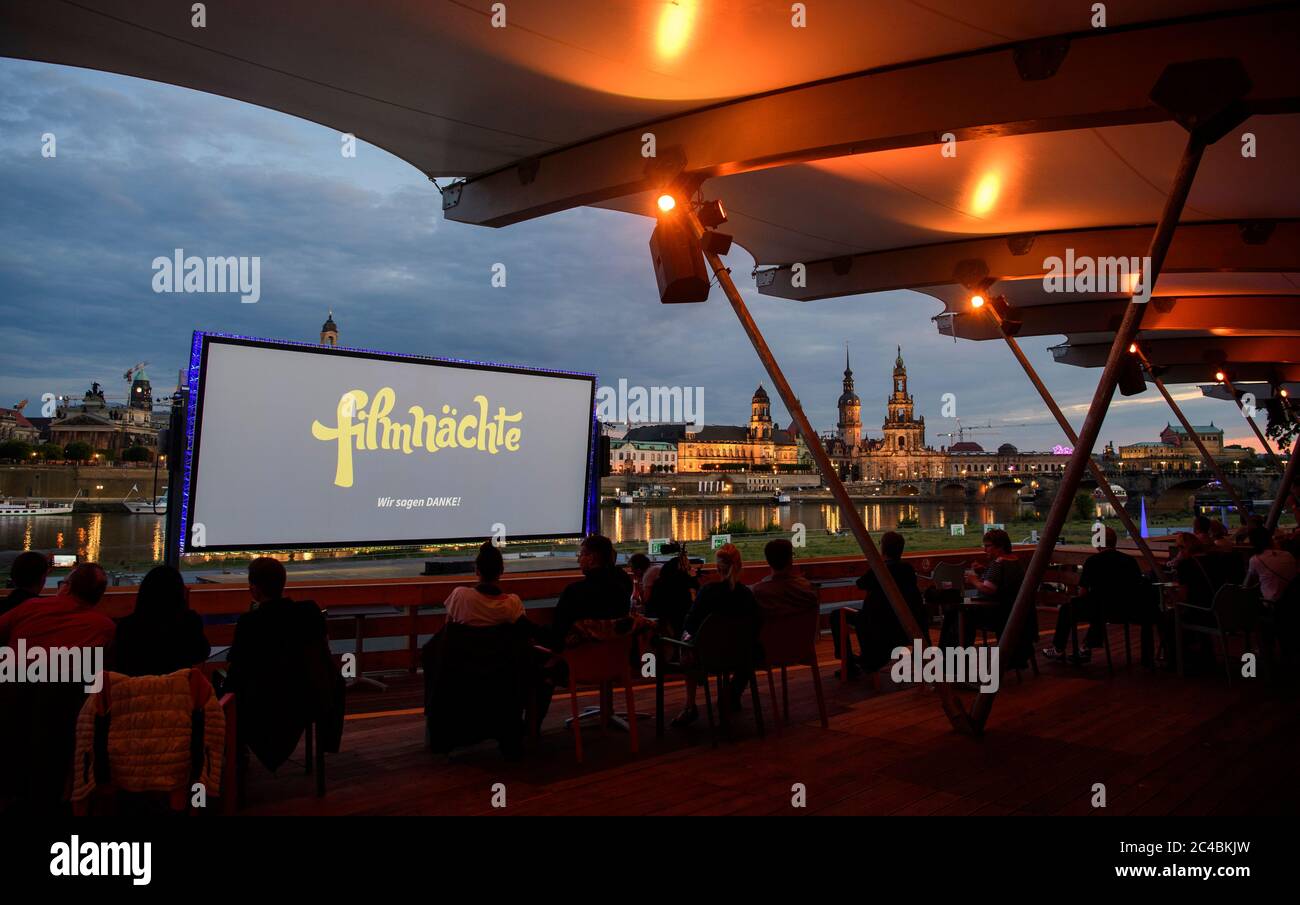 25 June 2020, Saxony, Dresden: Numerous guests of the "Film Nights on the  banks of the Elbe" sit in front of the backdrop of Dresden's old town with  the Frauenkirche (l-r), the