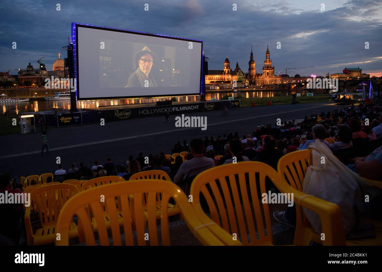 25 June 2020, Saxony, Dresden: Numerous guests of the "Film Nights on the  banks of the Elbe" sit in front of the backdrop of Dresden's Old Town with  the City Hall (l-r),