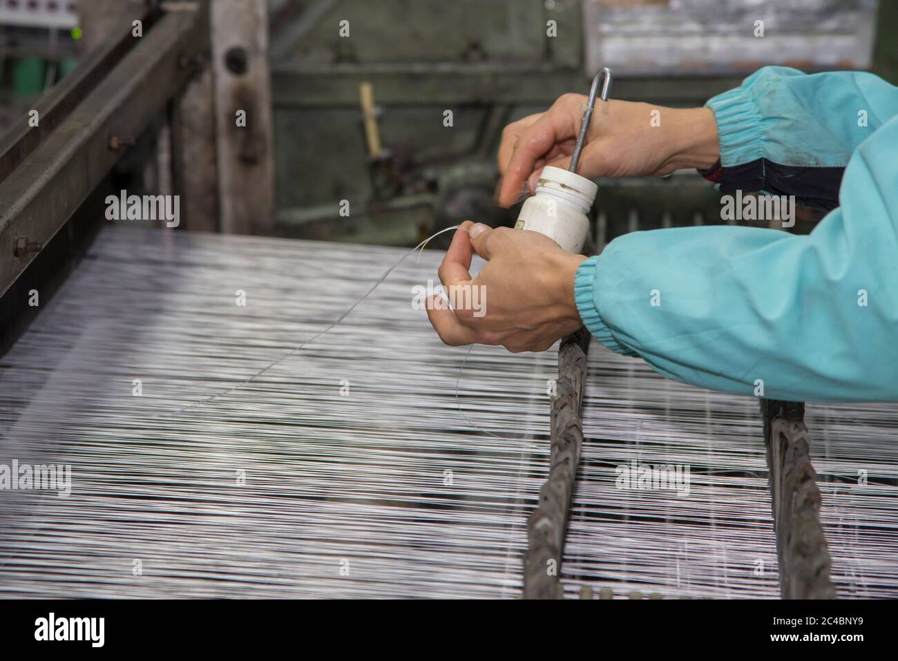 Worker's hands, fiberglass mesh making machine at factory, building