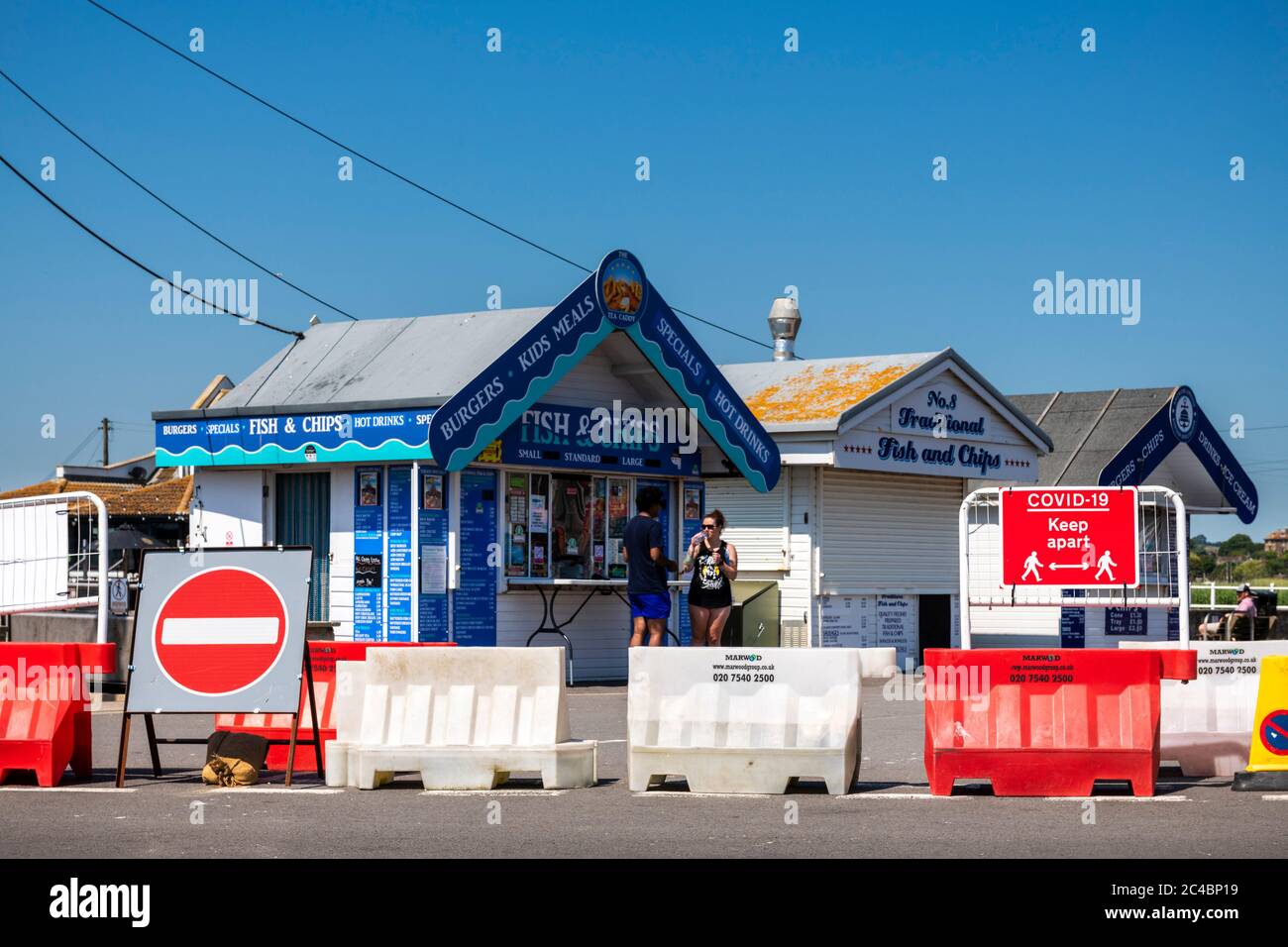 Covid-19 social distancing, where the road has been closed to make room for people queuing at seaside food huts, West Bay, Dorset, UK. Stock Photo