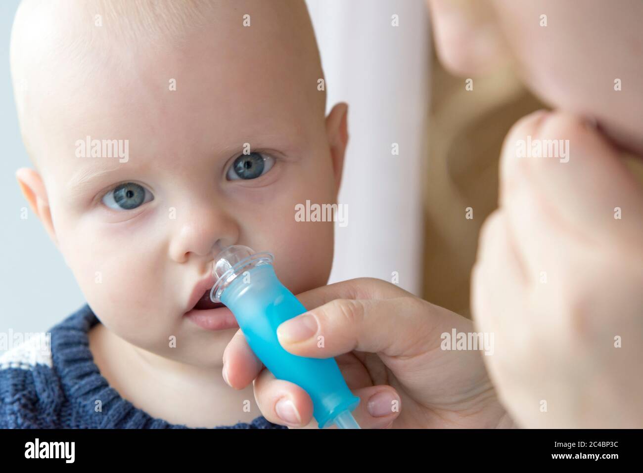 Mom cleans baby's nose from mucus using a nasal aspirator Stock Photo