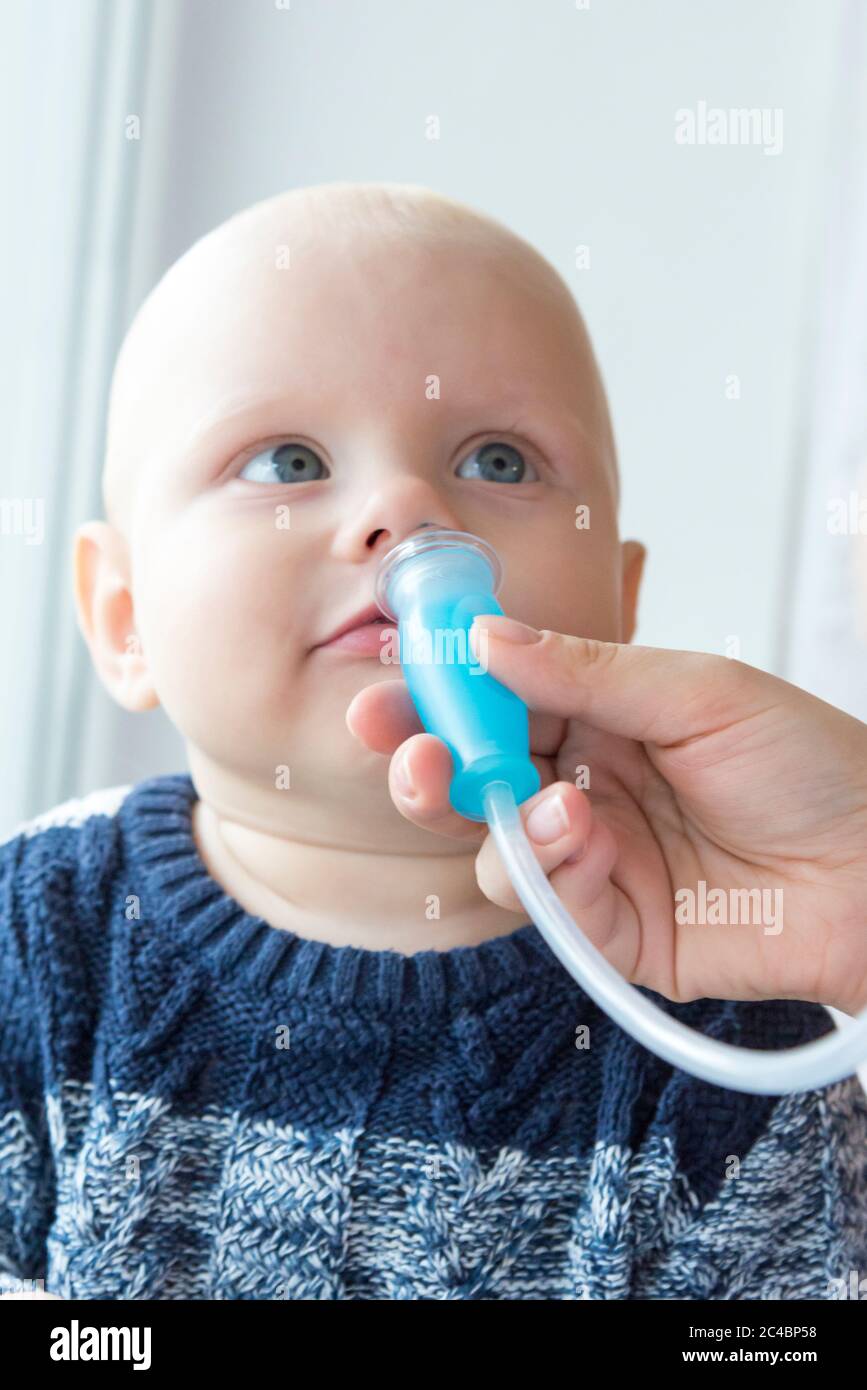 Mom cleans baby's nose from mucus using a nasal aspirator Stock Photo