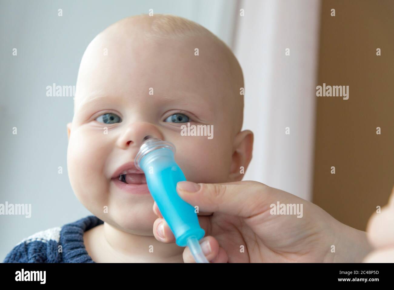 Mom cleans baby's nose from mucus using a nasal aspirator Stock Photo