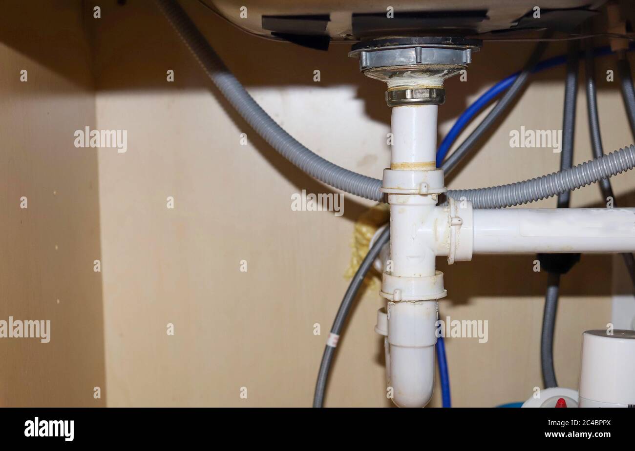 A close up image of leaking PCV pipes under a kitchen sink Stock Photo -  Alamy