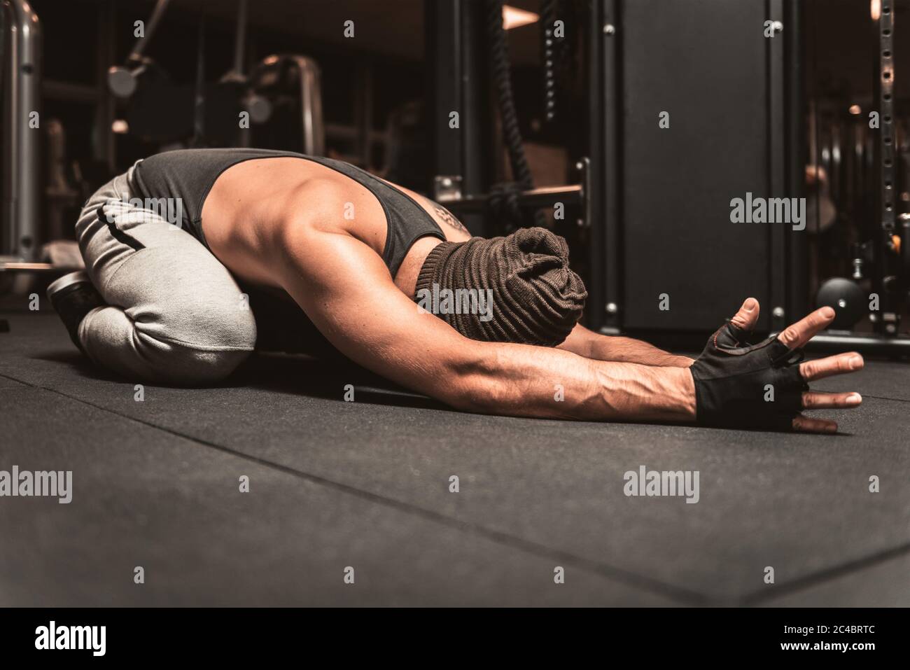 A sporty man in the gym is doing Yoga exercises. Back stretch exercise. Yoga position - Sasangasana. Yoga mental benefits. Stock Photo