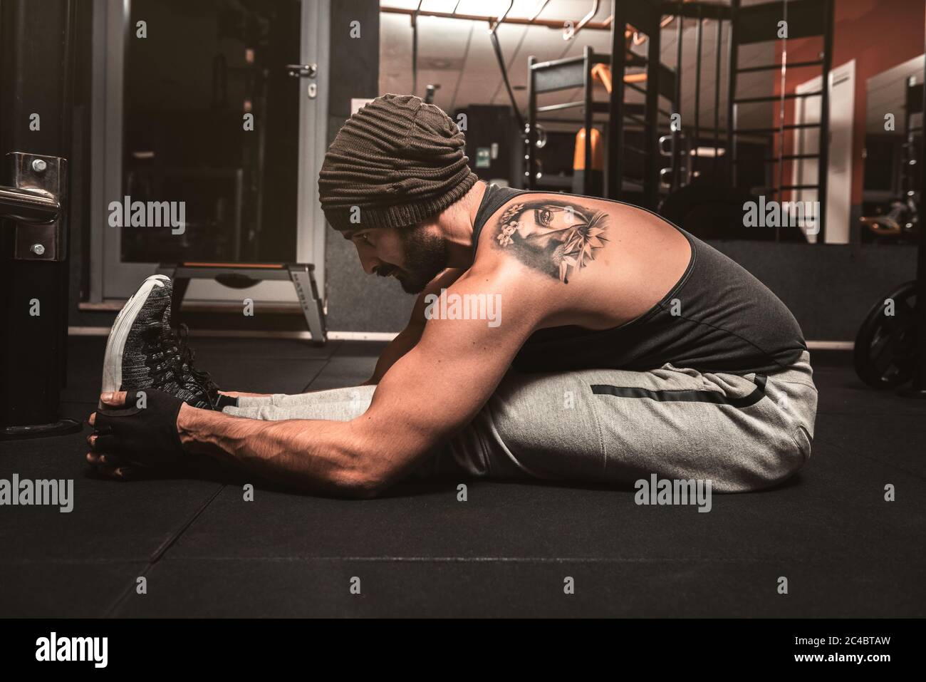 A sporty man in the gym is doing Yoga exercises. Paschimottanasana position: forward bending when seated. Yoga mental benefits. Stock Photo