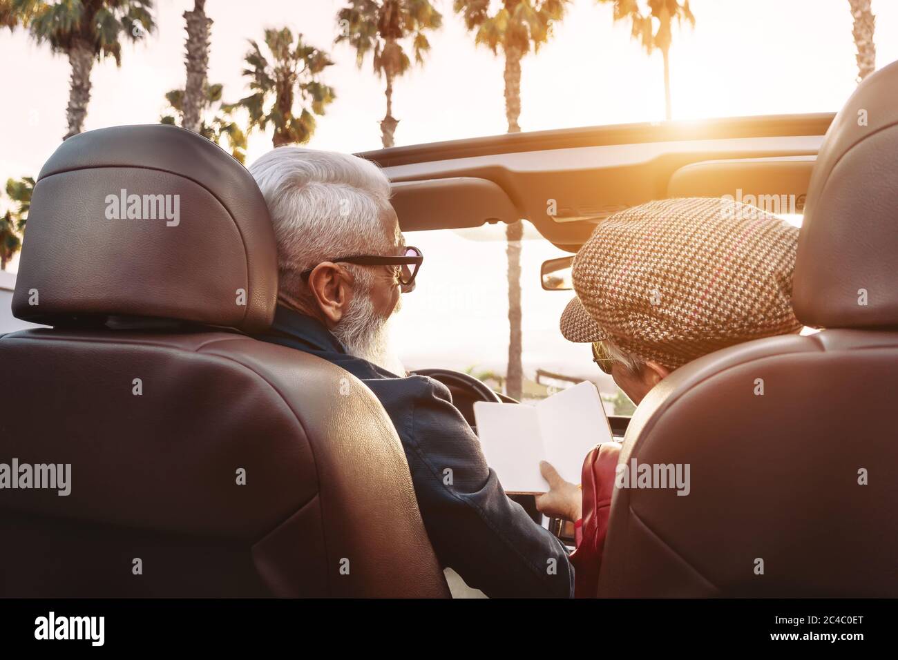 Happy senior couple having fun on new convertible car - Mature people enjoying time together during road trip vacation Stock Photo