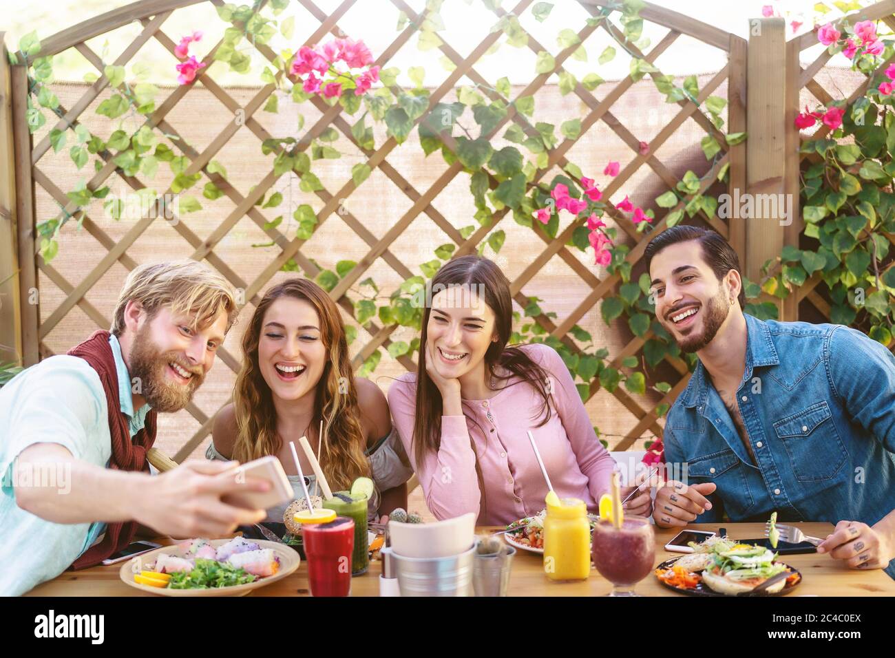 Happy friends taking selfie with mobile smartphone while lunching in coffee brunch restaurant - Young trendy people having fun eating together Stock Photo
