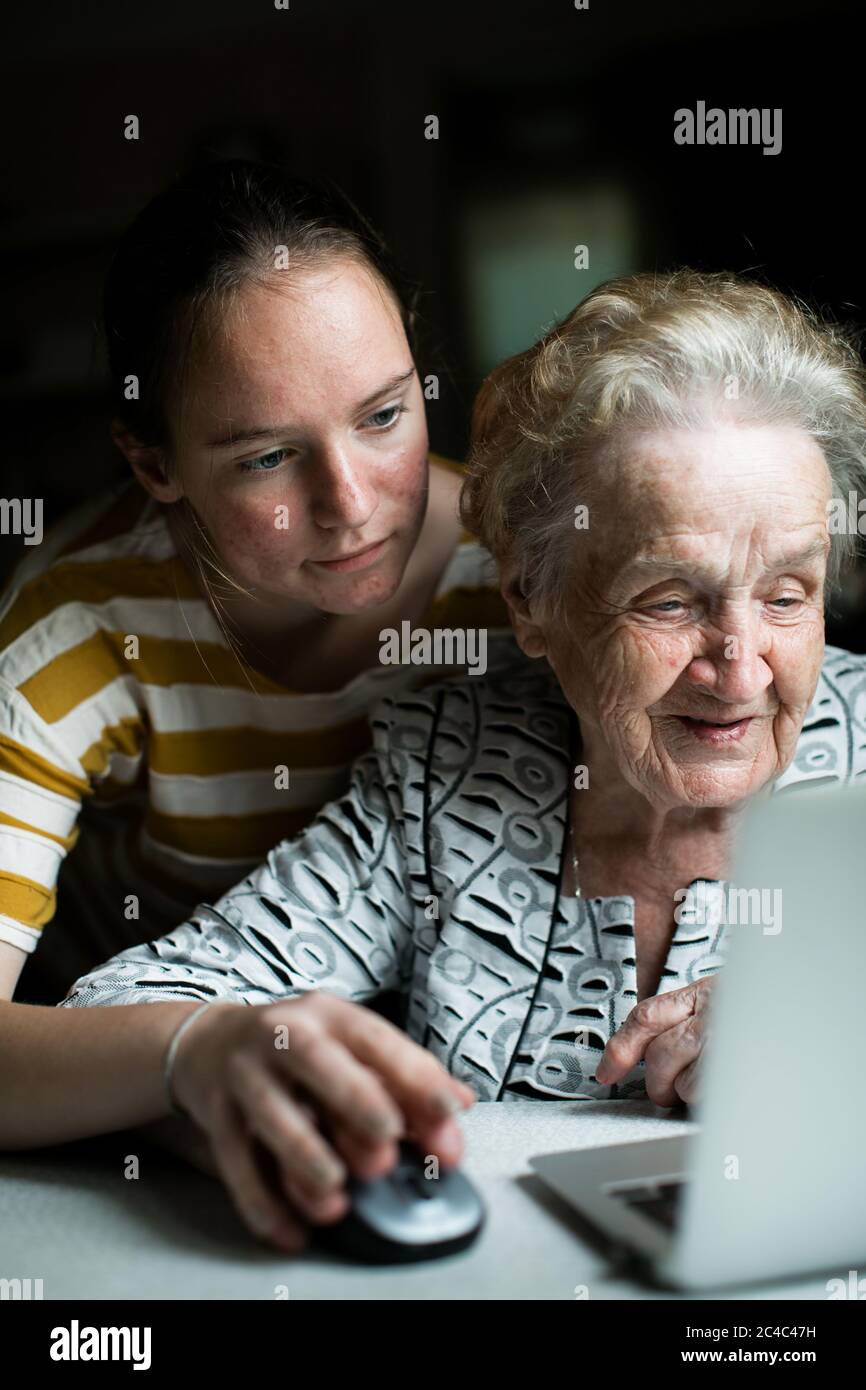 A girl teaches her grandmother to use a computer. Stock Photo