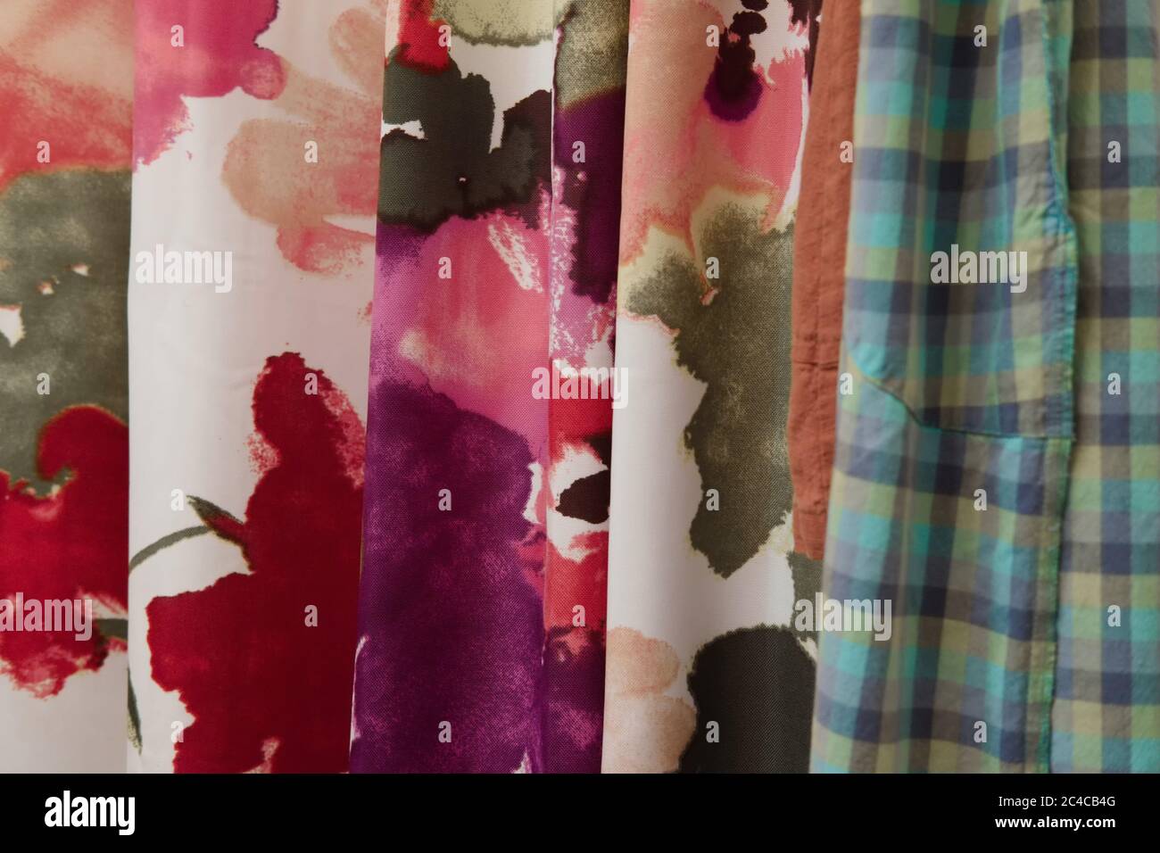 Multi-colored abstract floral and plaid fabric samples hanging vertically. Stock Photo