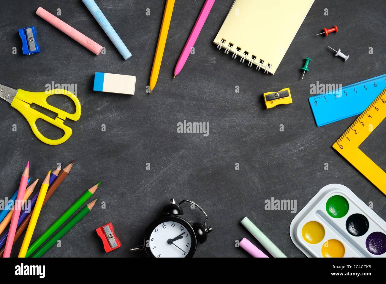 Frame of colorful school supplies on blackboard background. Back to ...