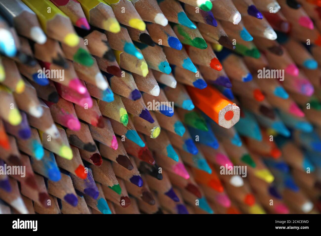 A large stack of masses of sharp multi colored pencils with one turned around facing the wrong way. Not fitting in, different, alternative, standing o Stock Photo
