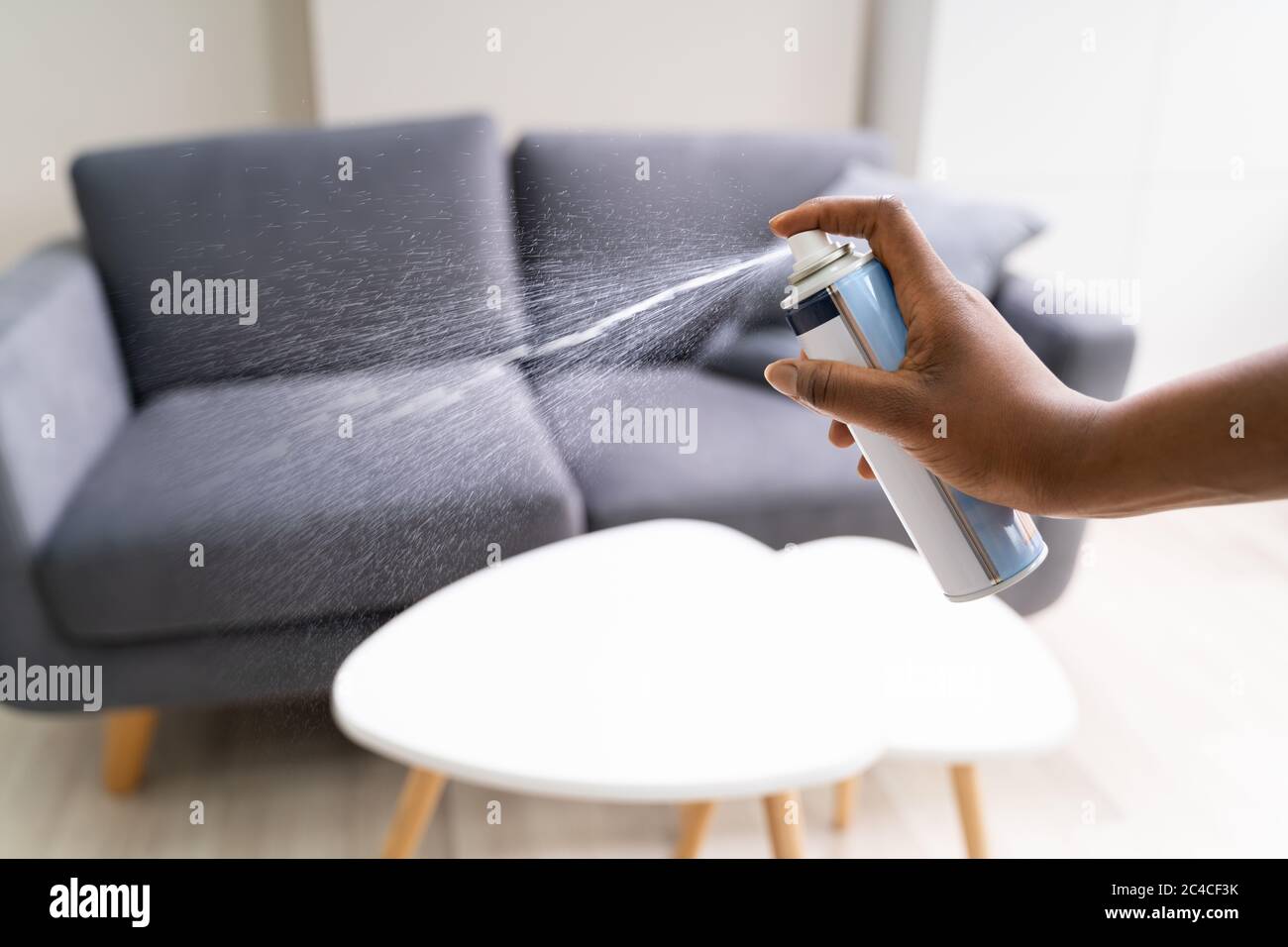 African Woman Using Living Room Air Spray Stock Photo
