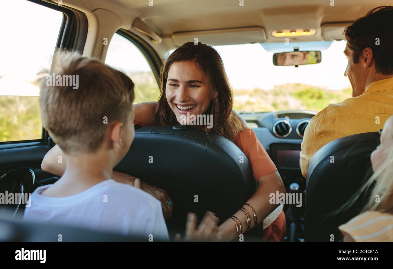 Happy family driving in a car. Woman playing with her children sitting in backseat od the car. Stock Photo