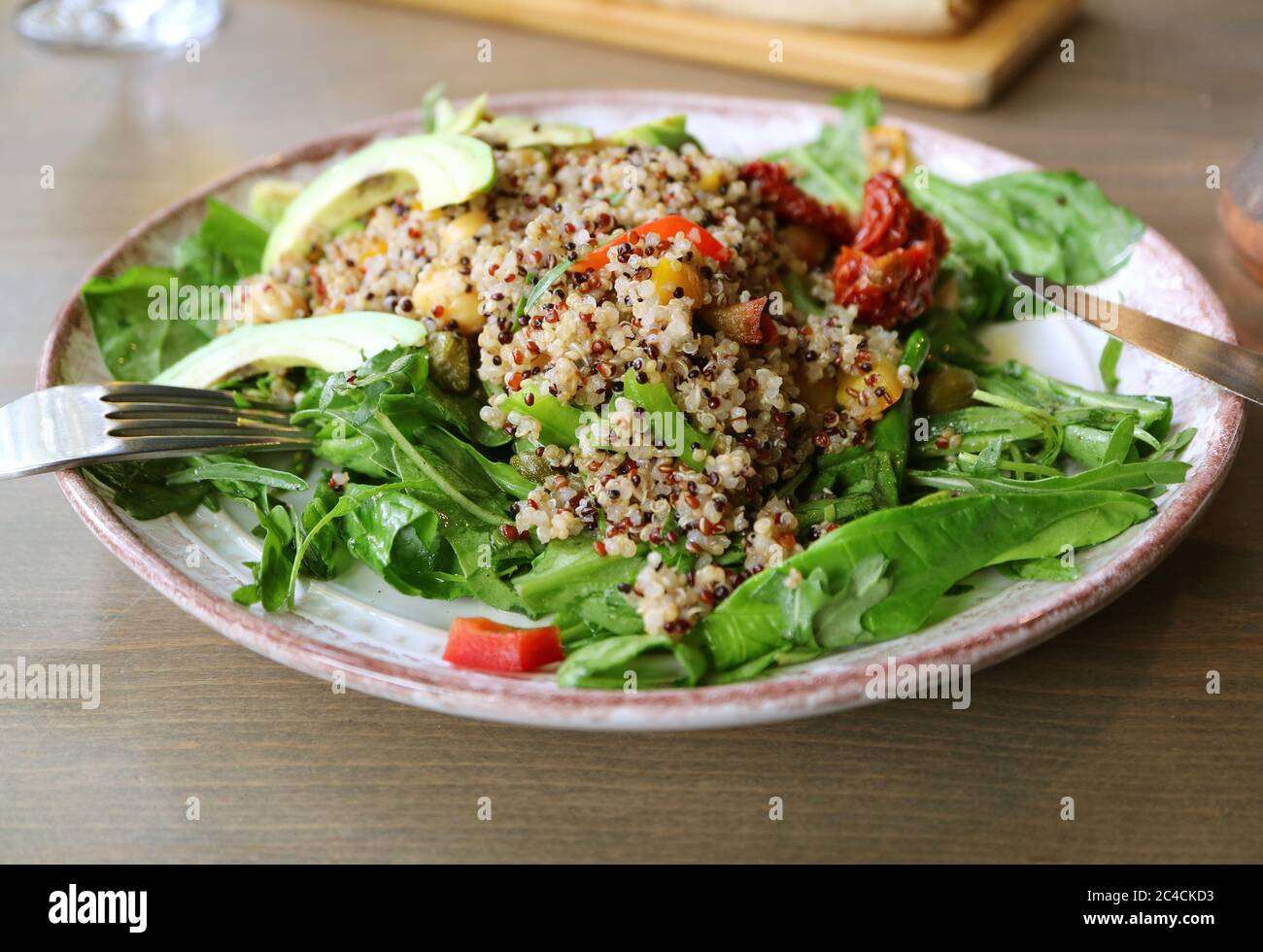 Plate of Quinoa Salad with Arugula and Avocado Served on Wooden Table Stock Photo
