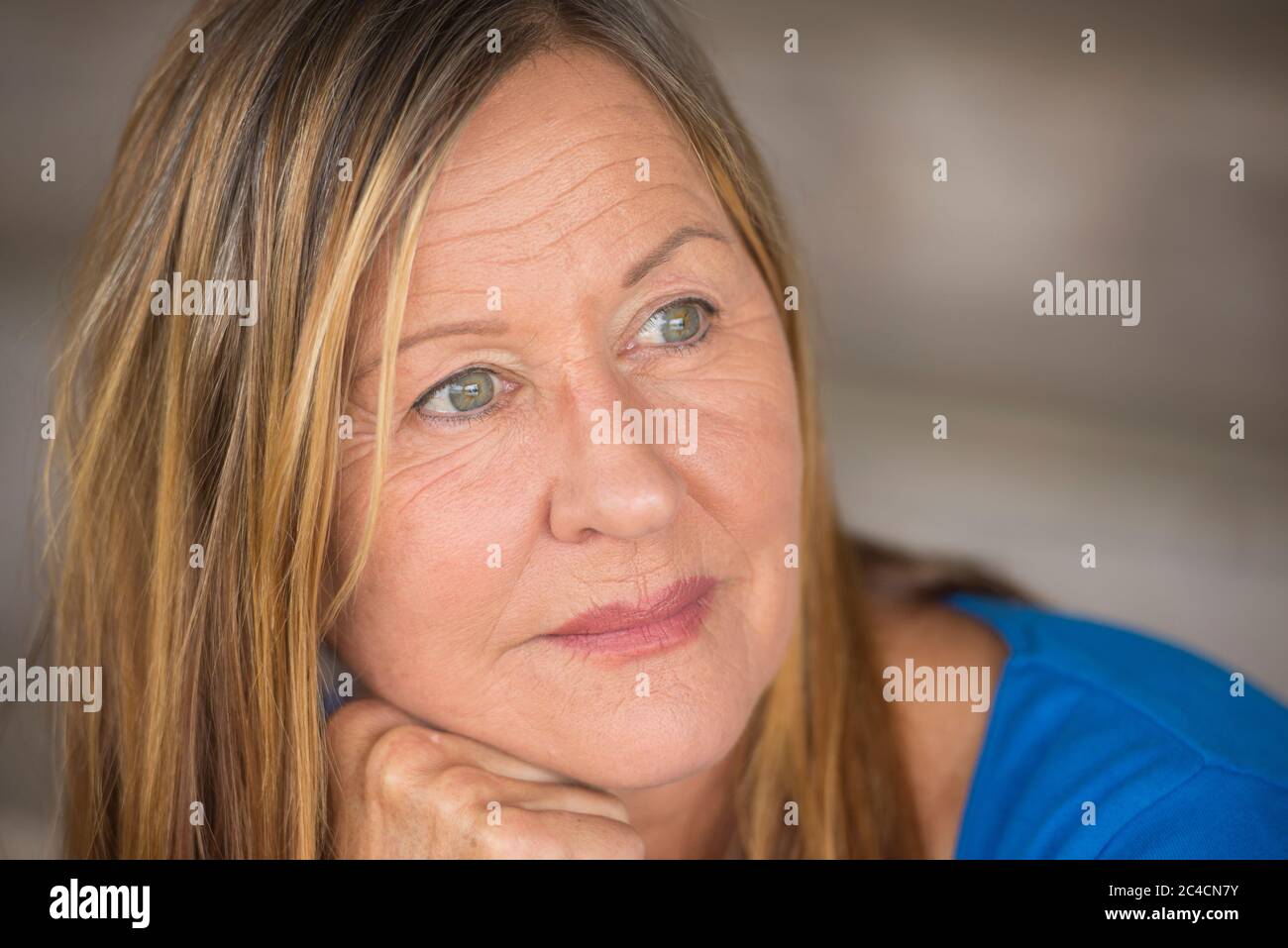 Portrait attractive mature woman with thoughtful serious facial expression, relaxed, laid back, peaceful daydreaming, blurred background. Stock Photo