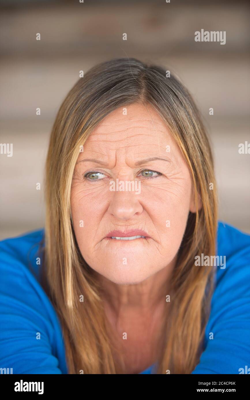 Portrait attractive mature woman with worried nervous thoughtful angry expression, , blurred background. Stock Photo