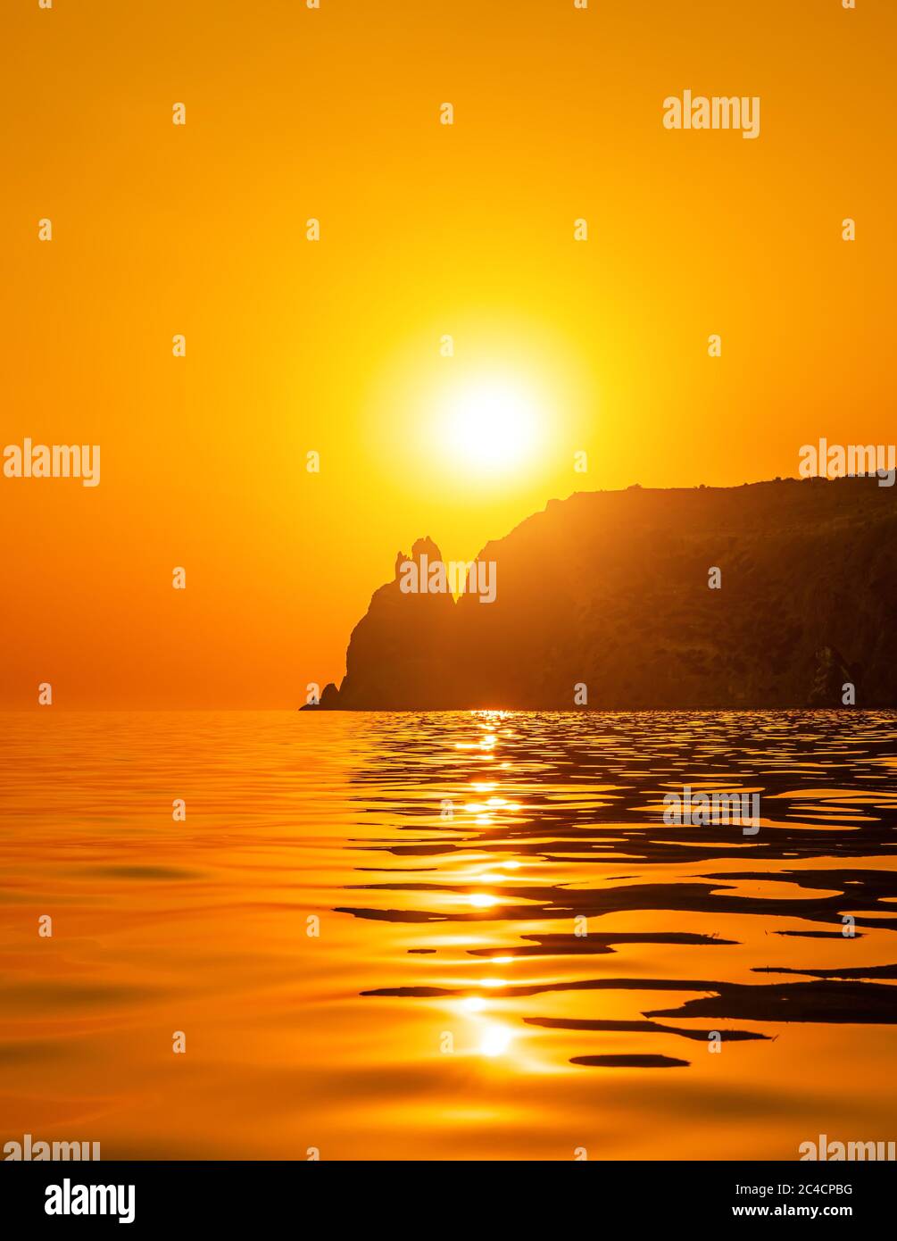 A red burning sunset with the silhouette of a cliff over the sea. Copy ...