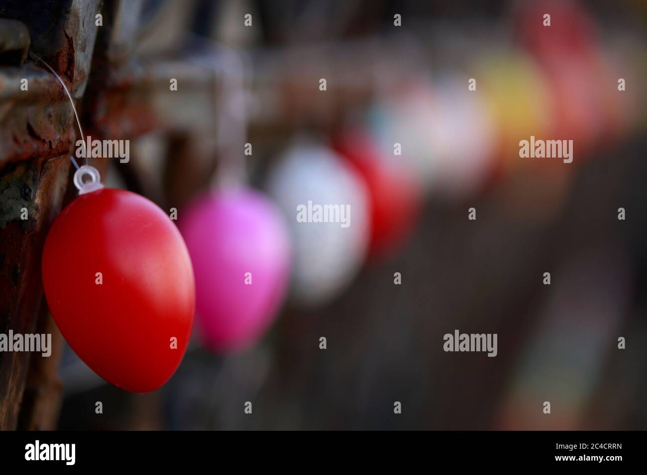 Colorfully colored Easter eggs hang in a row on an old garden fence, Bremen, Germany Stock Photo