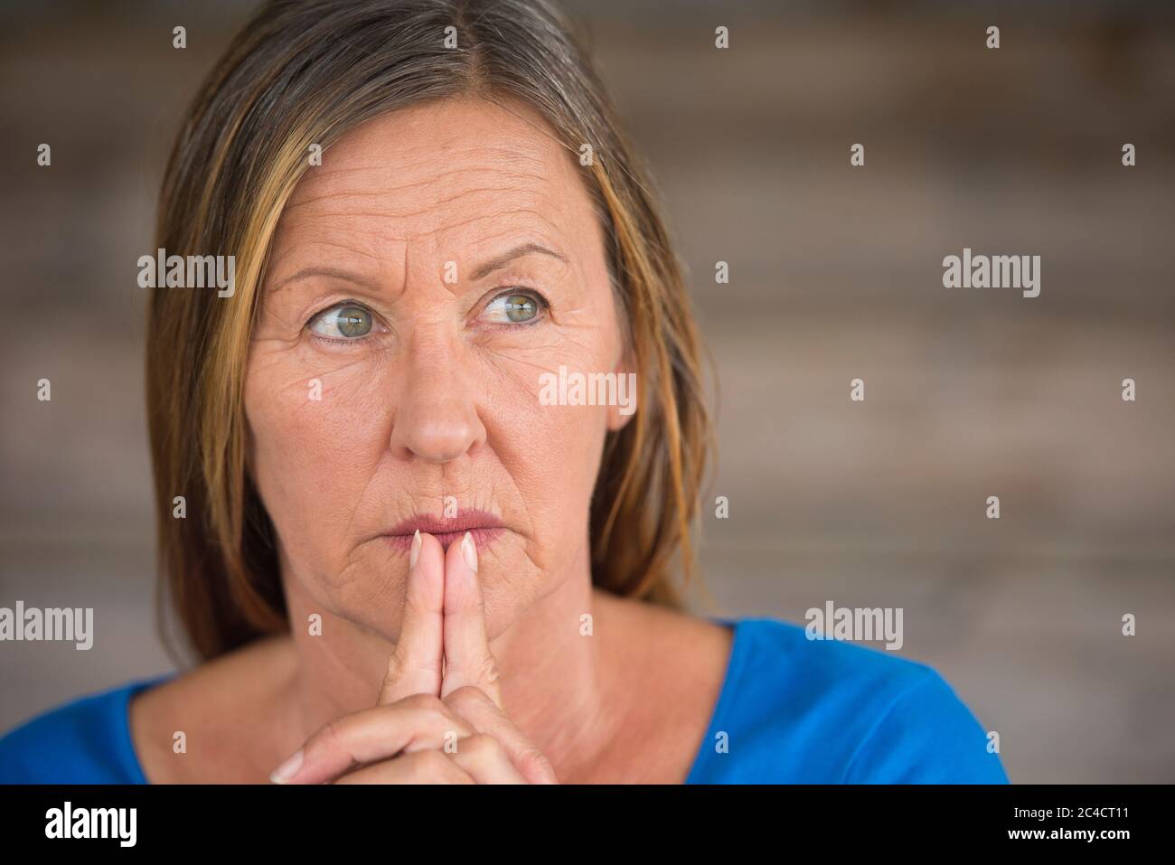 Portrtait attractive religious mature woman praying with folded hands, thoughtful, hopeful, meditating, blurred background, copy space. Stock Photo