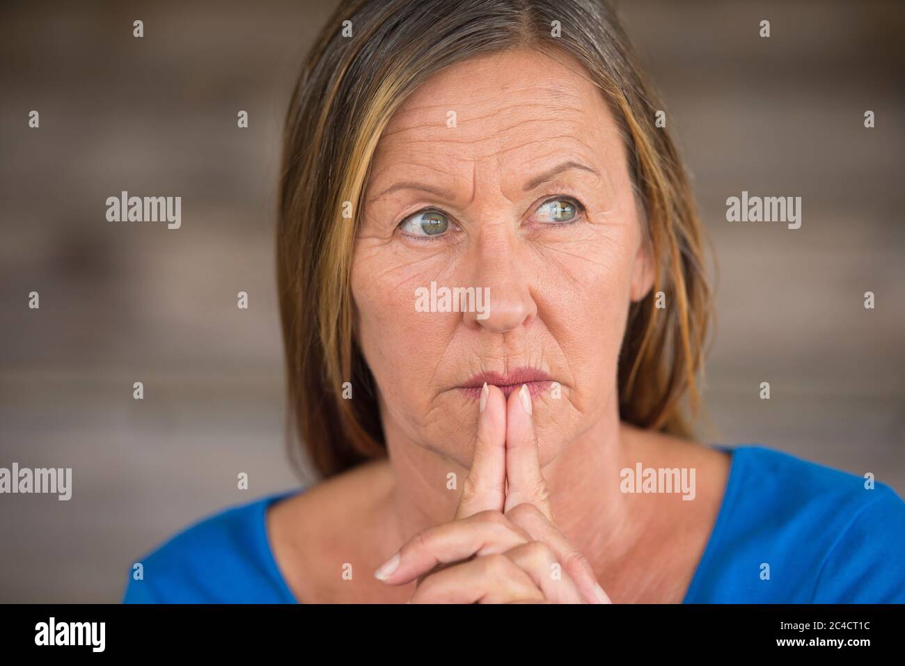 Portrtait attractive religious christian mature woman praying with folded hands, thoughtful, hopeful, meditating, blurred background, copy space. Stock Photo