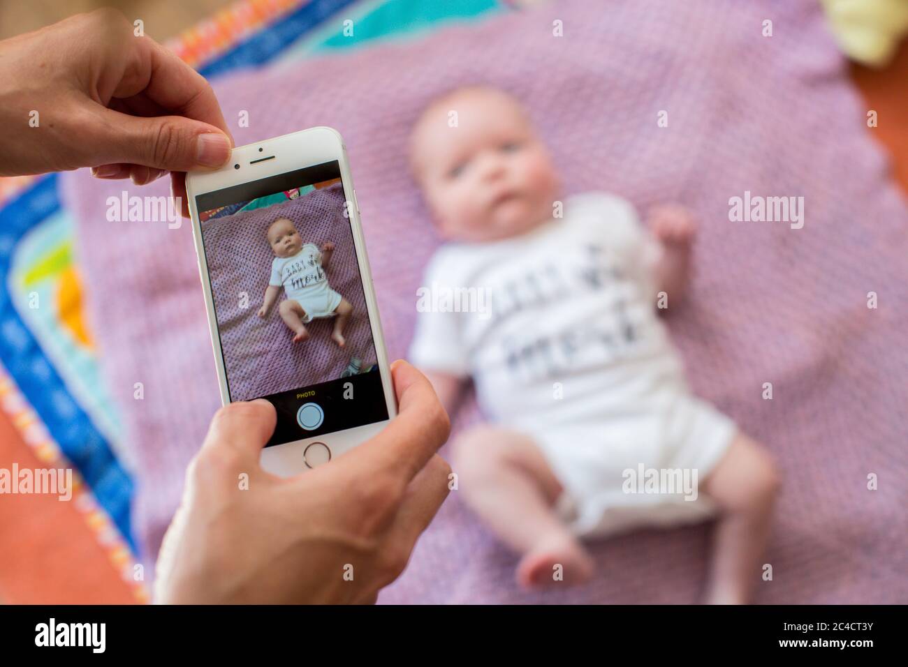 A woman's hand taking photos of a newborn baby boy using a mobile phone. Photo by Sam Mellish Stock Photo