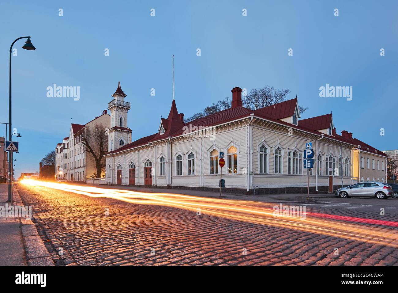Evening cityscape in the city of Kotka in Finland. A street in the old town paved with stone, a wooden old building of fire department. Stock Photo