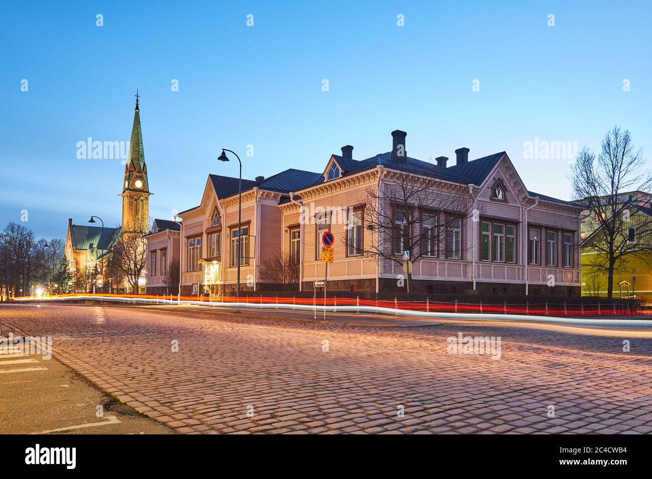 Evening cityscape in the city of Kotka in Finland. A street in the old town paved with stone, a wooden building and a church against the night sky. Stock Photo