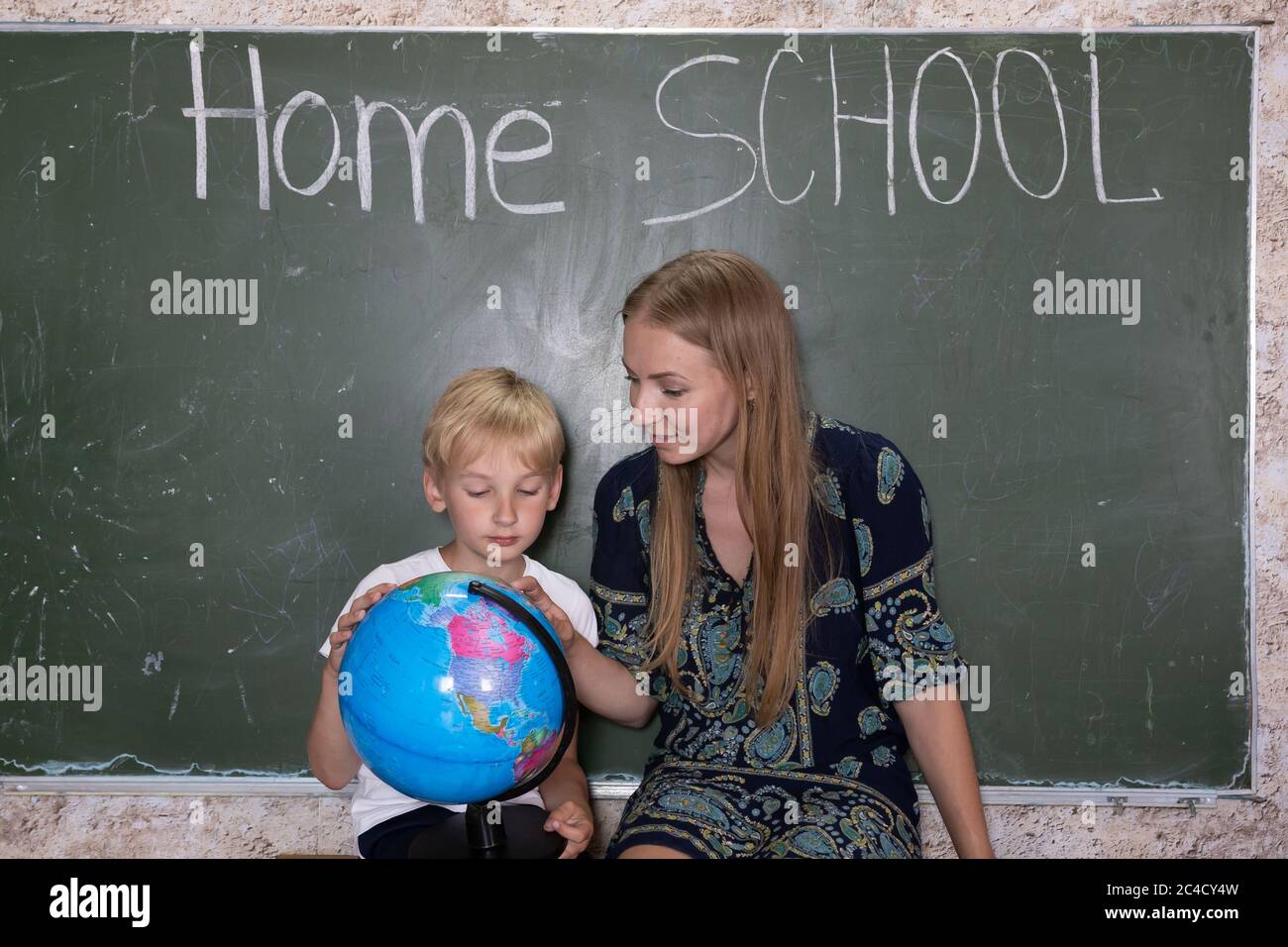 Mother is studying a world map on a globe with her son. Stock Photo