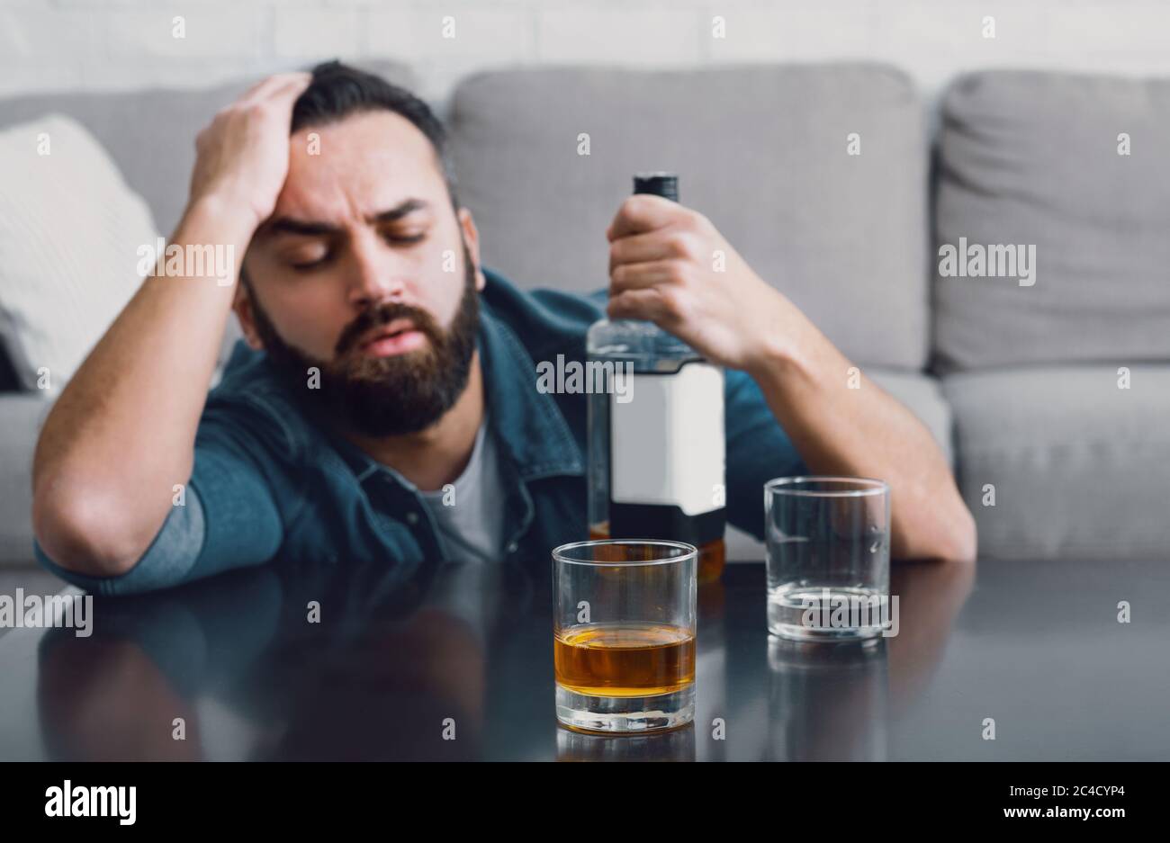 Depression and alcoholism at home. Man falls asleep and holding bottle Stock Photo