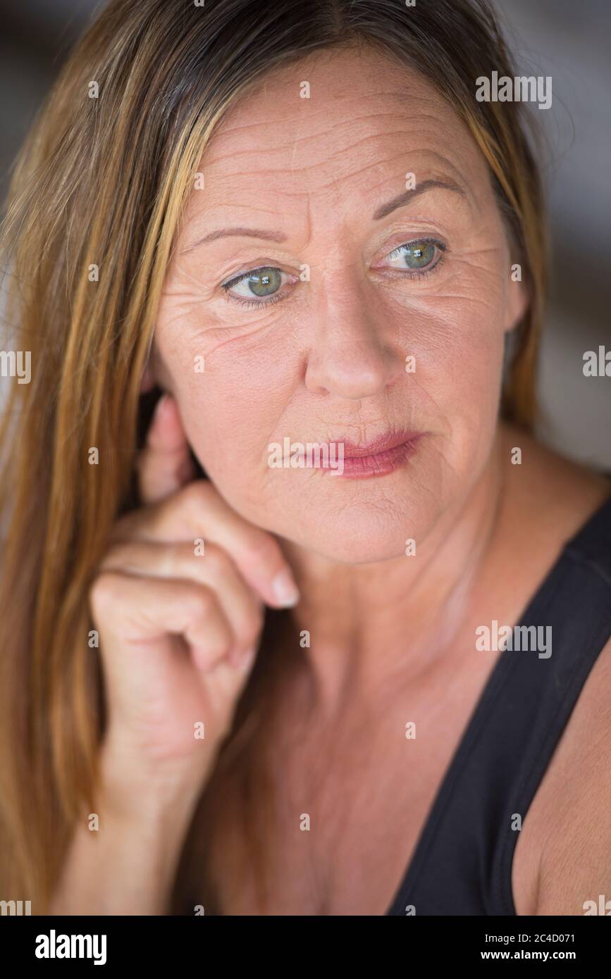 Portrait attractive mature woman, thoughtful serious facial expression, blurred background. Stock Photo