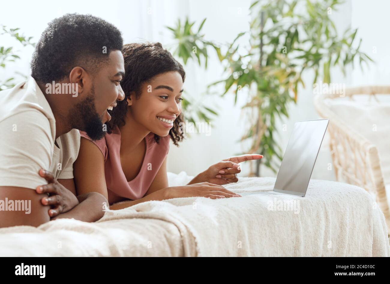 Side view of cheerful african couple using laptop in bed Stock Photo ...