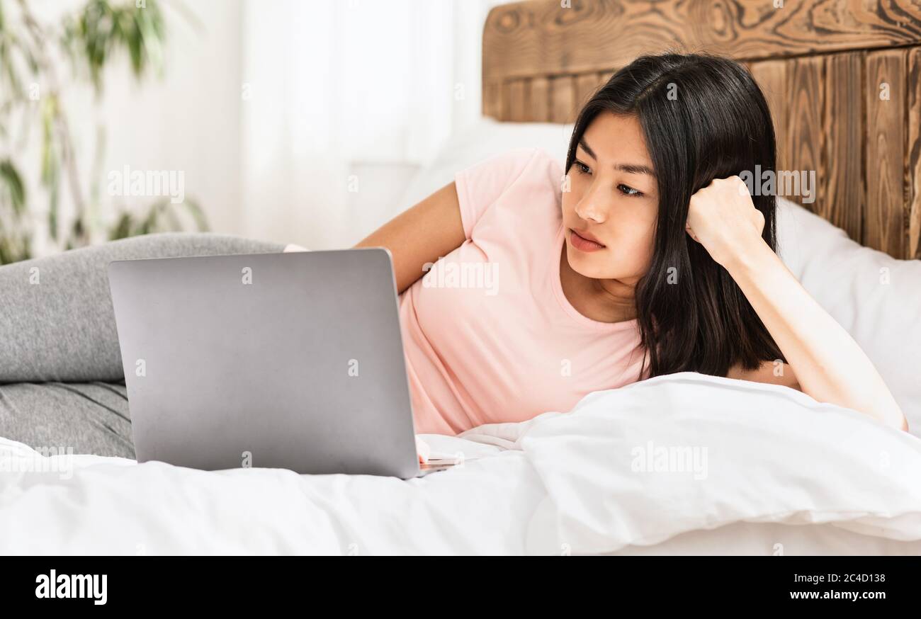 https://c8.alamy.com/comp/2C4D138/chinese-woman-working-on-laptop-lying-in-bed-at-home-2C4D138.jpg