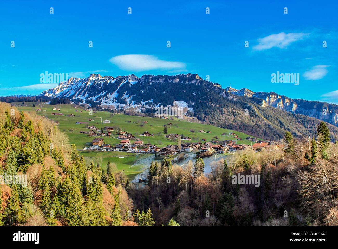spectacular view of the snow-capped mountains in winter at Sigriswil in the district of Thun - Bern, Switzerland. Panorama with houses, grass, green, Stock Photo