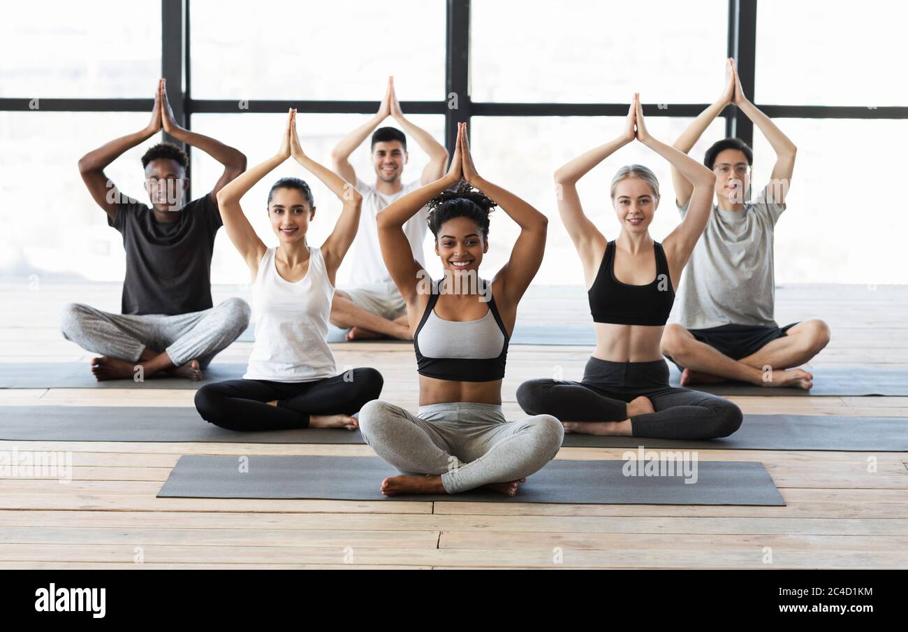 Multiethnic group of young sporty people practicing yoga indoors Stock Photo