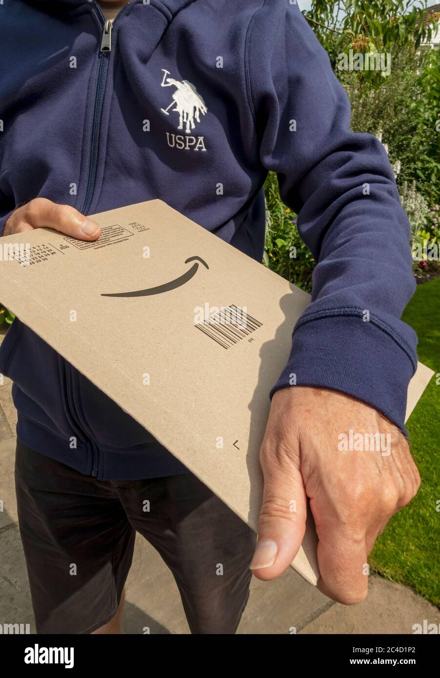 Close up of man person holding Amazon delivery parcel packet package home internet shopping England UK United Kingdom GB Great Britain Stock Photo