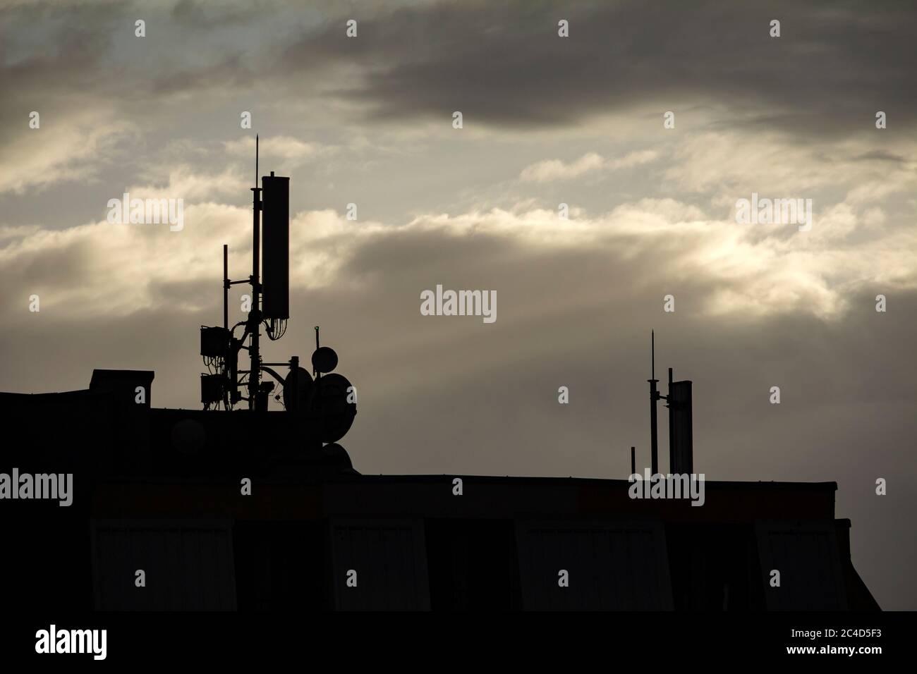 Cell phone tower silhouette on cloudy background Stock Photo