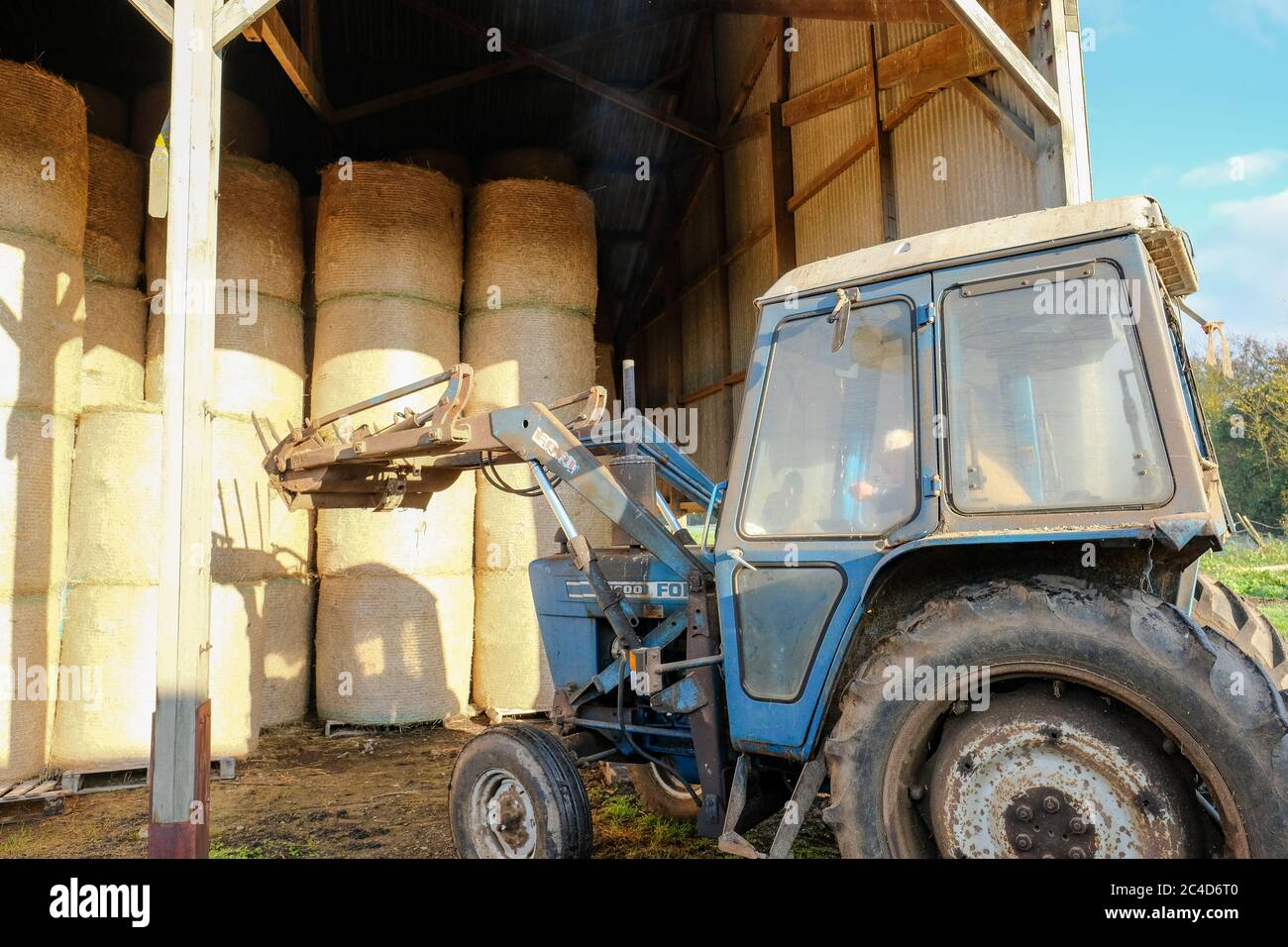 Farmer seen in his tractor, about to pick up a very large and heavy