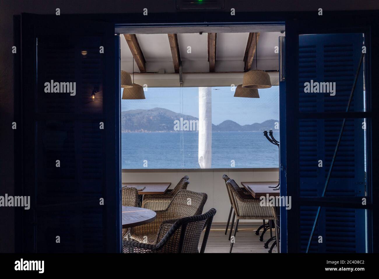 Silhouette of doors opening to a room with tables and chairs by a lake