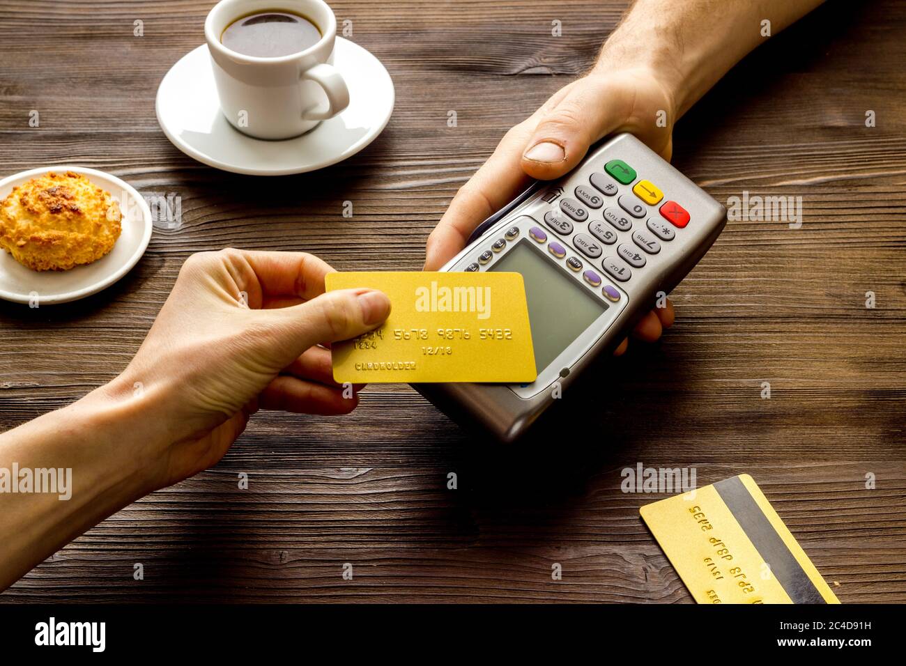 Payment transactions. Hand hold card near terminal on wooden cafe table ...