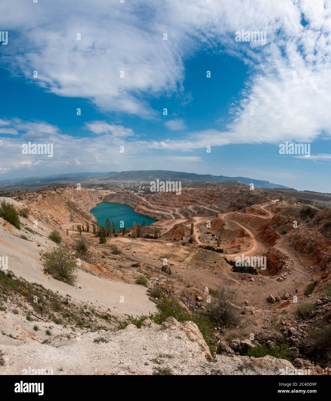 Emerald lake in a flooded quarry. Emerald green lake in flooded opencast mine, open pit. Oval lake in mining industrial crater, acid mine drainage in Stock Photo