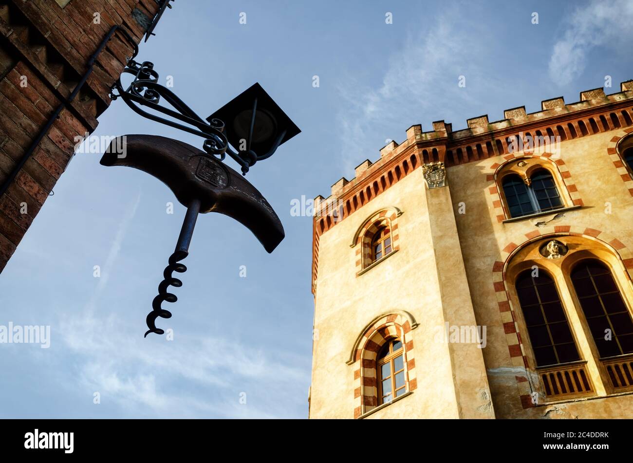 The castle of Barolo (Piedmont, Italy) with a giant wine corkscrew hanging from a town lamp Stock Photo