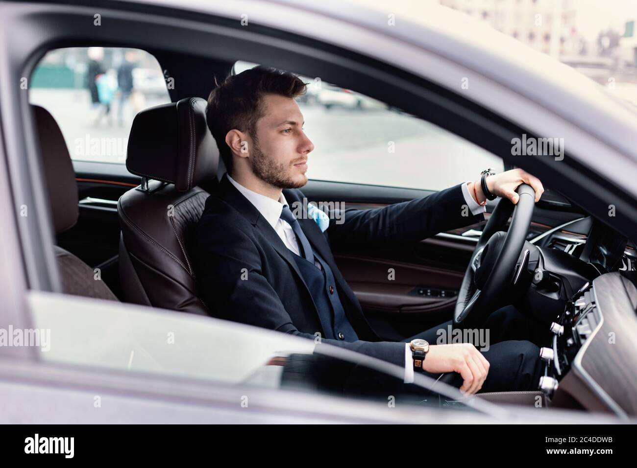 Confident man wearing suit and luxury watch driving car Stock Photo Alamy