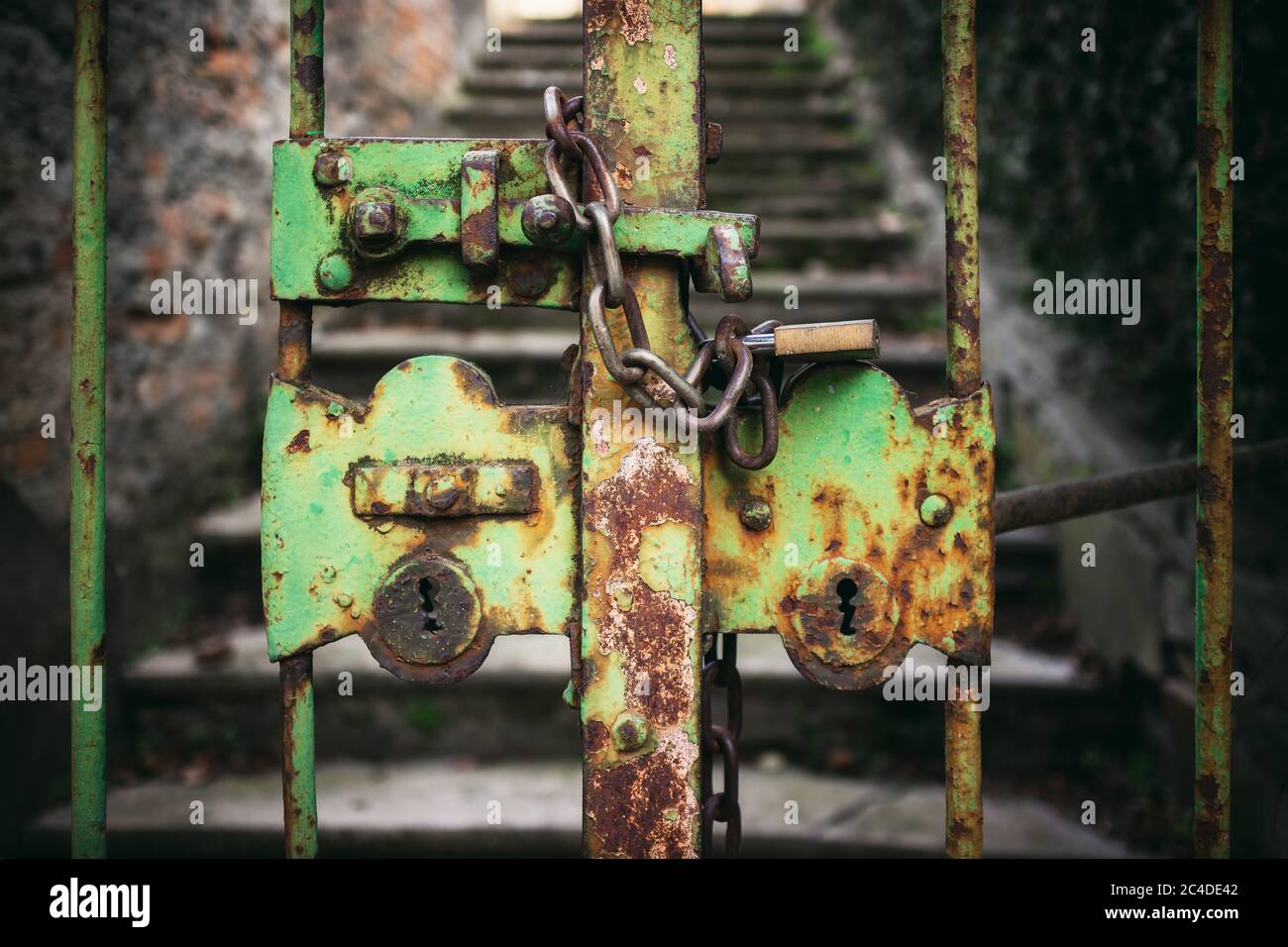 exterior view of a really old, closed and rusty green iron gate with chain and padlock Stock Photo
