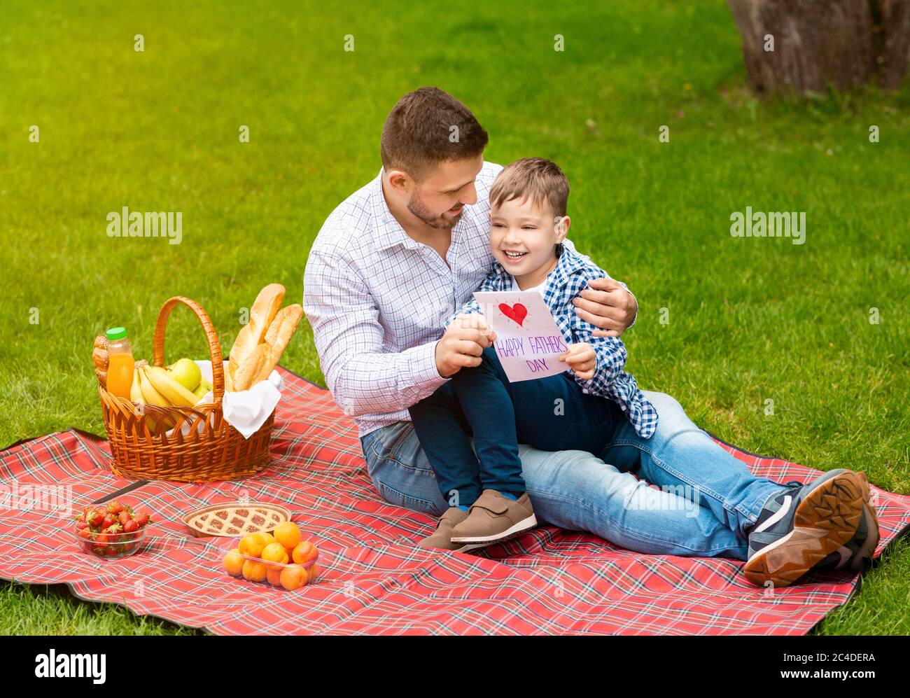 Happy family times. Dad with greeting card and his adorable little boy celebrating father's day on picnic outside Stock Photo